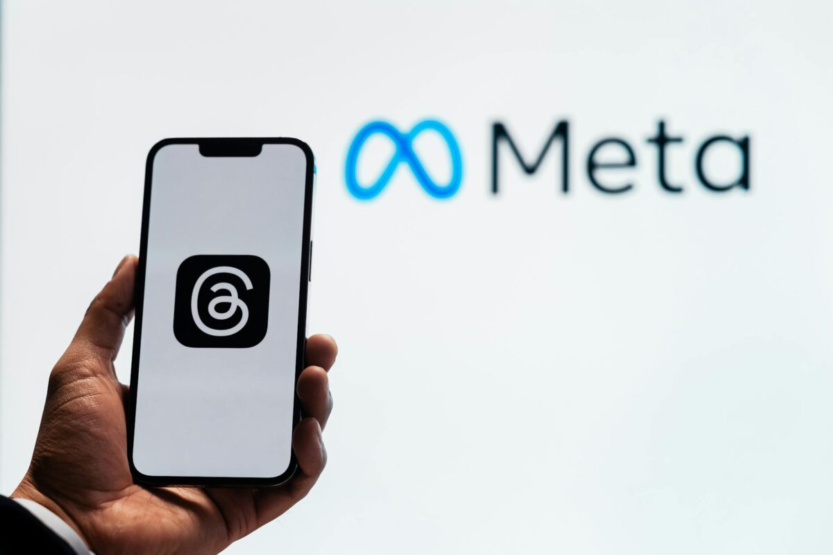 Holding a smartphone with the threads app with the meta platforms logo in the background